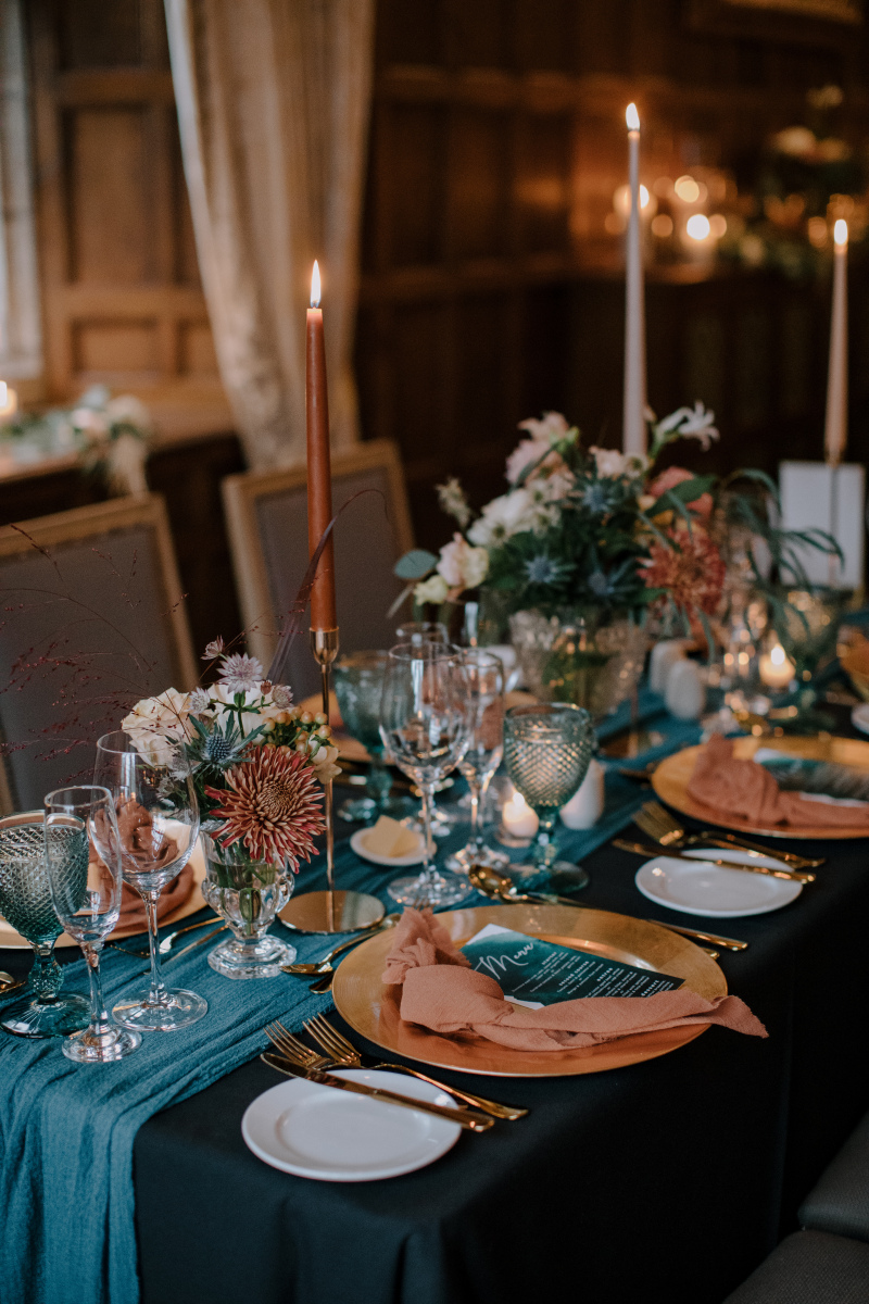 You can mix table cloths with table runners: here we did a black base cloth and added a turquoise fabric runner to hit our moody peacock color palette.